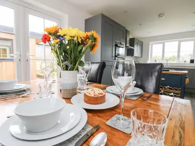 a dining room table with a cake and flowers on it at Beacon House in St. Agnes