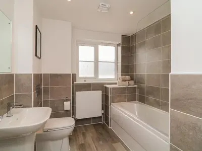 a bathroom with a tub and a toilet and a sink at Beacon House in St. Agnes