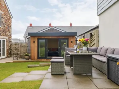 a backyard patio with a couch and a table at Beacon House in St. Agnes
