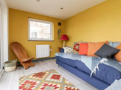 a living room with a blue couch and a window at Beacon House in St. Agnes