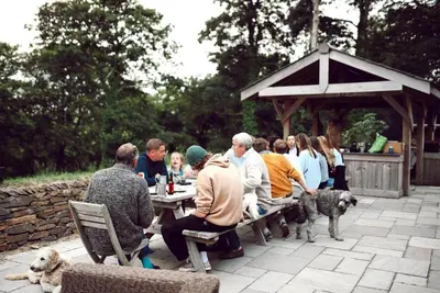 a group of people sitting at a table with a dog at Glamping Yurts near Newquay in Newquay