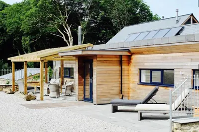 a wooden cabin with a bench and a porch at Glamping Yurts near Newquay in Newquay