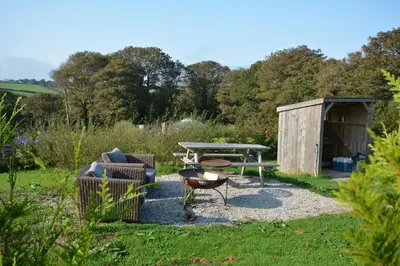 a garden with a picnic table and a barbecue at Glamping Yurts near Newquay in Newquay