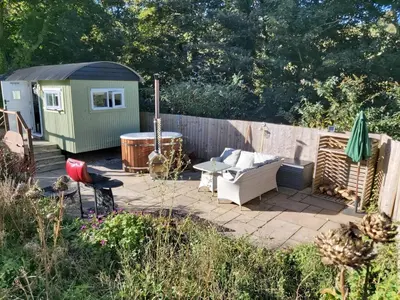 a backyard patio with a hot tub and a shed at Luxury Coastal Shepherds Hut with hot tub, dining dome & a 5 Minute Walk to Pubs and Village in Polperro