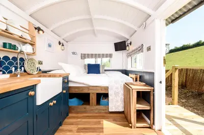 a bedroom in a tiny house with a bed at Luxury Coastal Shepherds Hut with hot tub, dining dome & a 5 Minute Walk to Pubs and Village in Polperro