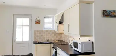 a kitchen with white cabinets and a microwave at Amazing Granite Henge and Swimming Pool in Looe