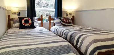 two twin beds in a room with a window at Amazing Granite Henge and Swimming Pool in Looe