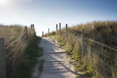 a dirt path through a field with a fence at Towennan - four bedroomed apartment in quiet seaside village. in Gwithian