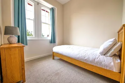 a bedroom with a bed and a window at Towennan - four bedroomed apartment in quiet seaside village. in Gwithian