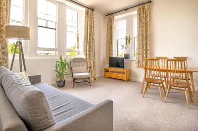 a living room with a couch and a table and chairs at Towennan - four bedroomed apartment in quiet seaside village. in Gwithian