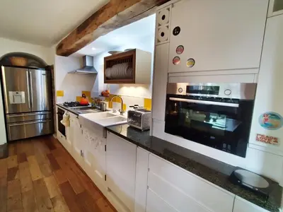 a kitchen with white cabinets and a black counter top at The Shire House in Lostwithiel