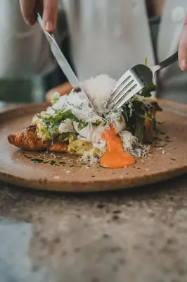 a person eating a plate of food with a fork and knife at Polzeath Beach House in Polzeath