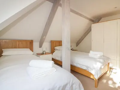 two beds in a attic room with white sheets at Stores & Supplies in Bodmin