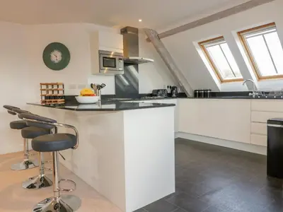 a kitchen with white cabinets and bar stools at Stores & Supplies in Bodmin