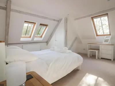 a white bedroom with a bed and a desk at Stores & Supplies in Bodmin