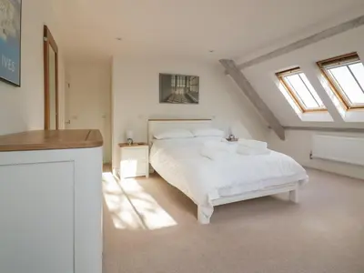 a white bedroom with a bed and windows at Stores & Supplies in Bodmin