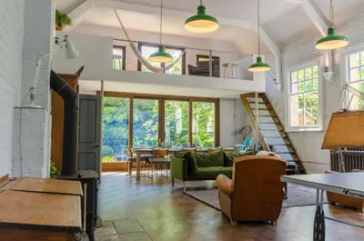 a living room with a green couch and a table at Luxury Victorian school with views of Harbour in Fowey