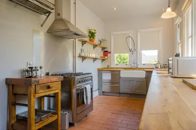 a large kitchen with a stove and a sink at Luxury Victorian school with views of Harbour in Fowey