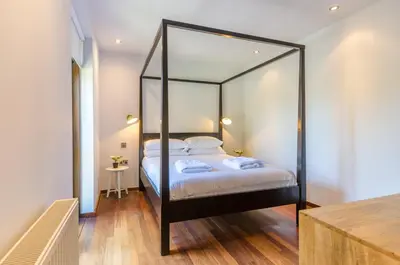 a bedroom with a black canopy bed with a mirror at Luxury Victorian school with views of Harbour in Fowey