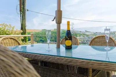 a bottle of wine sitting on a table with glasses at Luxury Victorian school with views of Harbour in Fowey