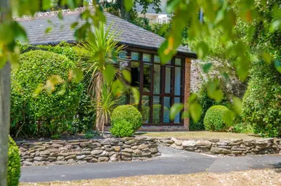 a house with a stone wall and windows at Luxury Victorian school with views of Harbour in Fowey