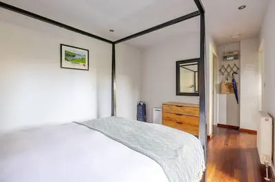 a bedroom with a white bed and a mirror at Charming Summerhouse Annexe in lush gardens in Fowey in Fowey