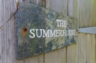 a rusty sign on the side of a wooden wall at Charming Summerhouse Annexe in lush gardens in Fowey in Fowey