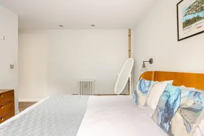 a bedroom with a white bed with a wooden headboard at Classroom Flat Suite in a converted school in Fowey town centre in Fowey