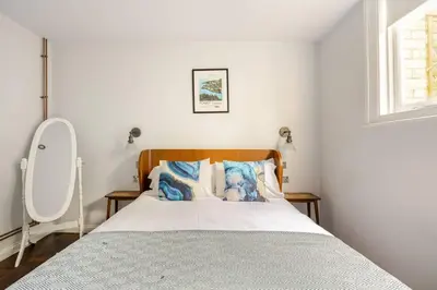 a bedroom with a bed with blue pillows and a mirror at Classroom Flat Suite in a converted school in Fowey town centre in Fowey