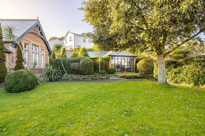 a house with a green yard with a tree at Classroom Flat Suite in a converted school in Fowey town centre in Fowey