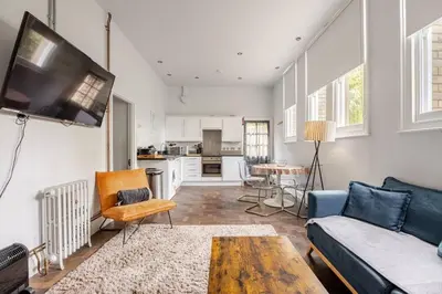 a living room with a couch and a tv at Classroom Flat Suite in a converted school in Fowey town centre in Fowey