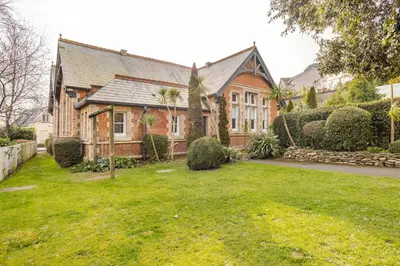a large brick house with a green yard at Classroom Flat Suite in a converted school in Fowey town centre in Fowey