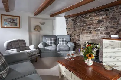 a living room with couches and a stone wall at Trevarrow Cottage in Coverack