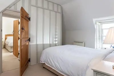 a white bedroom with a bed and a window at Trevarrow Cottage in Coverack