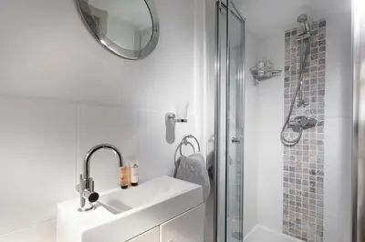 a white bathroom with a sink and a shower at Trevarrow Cottage in Coverack