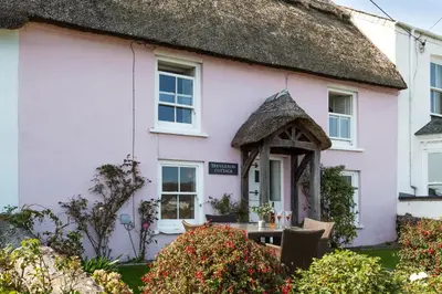 a pink house with a thatched roof at Trevarrow Cottage in Coverack