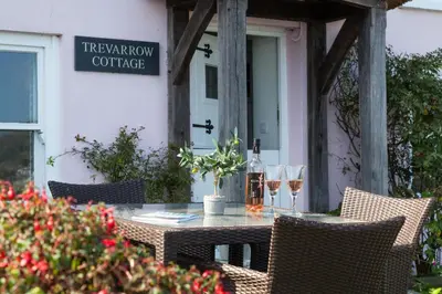 a table with two glasses of wine on a patio at Trevarrow Cottage in Coverack