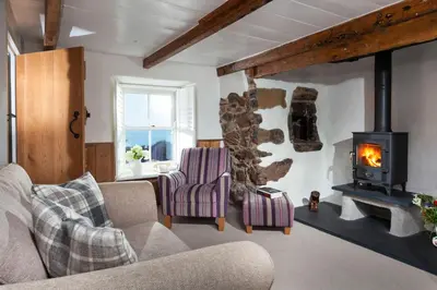 a living room with a fireplace and a couch at Trevarrow Cottage in Coverack
