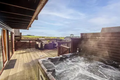 a hot tub on the deck of a house at Lodge 40 - Resort & Spa & Hot Tub & Free Wi-Fi in Saint Columb Major