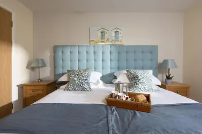 a bed with a blue headboard and a basket on it at Lodge 40 - Resort & Spa & Hot Tub & Free Wi-Fi in Saint Columb Major