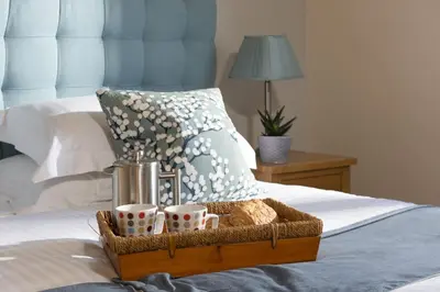 a tray with cups on a bed with a pillow at Lodge 40 - Resort & Spa & Hot Tub & Free Wi-Fi in Saint Columb Major
