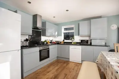 a kitchen with white cabinets and a table at Lodge 40 - Resort & Spa & Hot Tub & Free Wi-Fi in Saint Columb Major