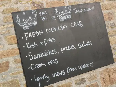 a sign with drawings on it on a brick wall at Nana's House in Marazion