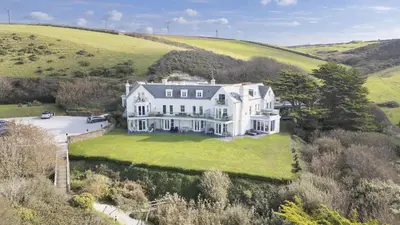 an aerial view of a large white house on a hill at 10 The Whitehouse, Watergate Bay in Mawgan Porth