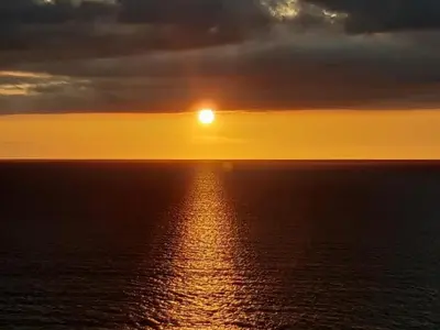 a sunset over the ocean with the sun in the sky at 67 Newquay Getaway in Porth