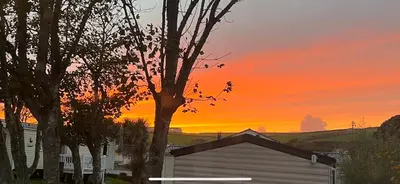a house with a tree in front of a sunset at 67 Newquay Getaway in Porth
