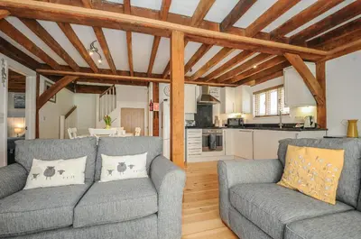 a living room with two couches and a kitchen at Stow Cottage in Camelford