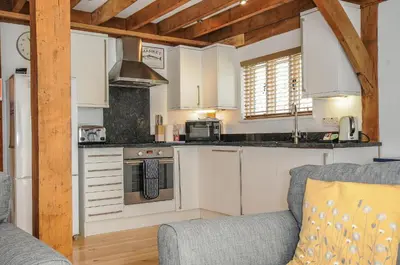 a kitchen with white cabinets and a gray couch at Stow Cottage in Camelford