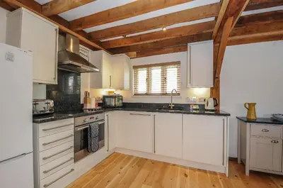 a kitchen with white cabinets and a wooden floor at Stow Cottage in Camelford