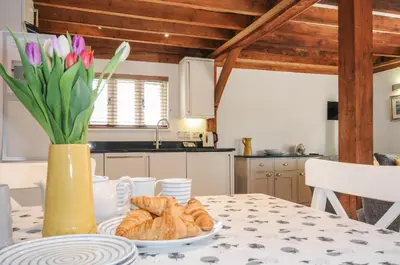 a table with a plate of croissants and a vase with flowers at Stow Cottage in Camelford